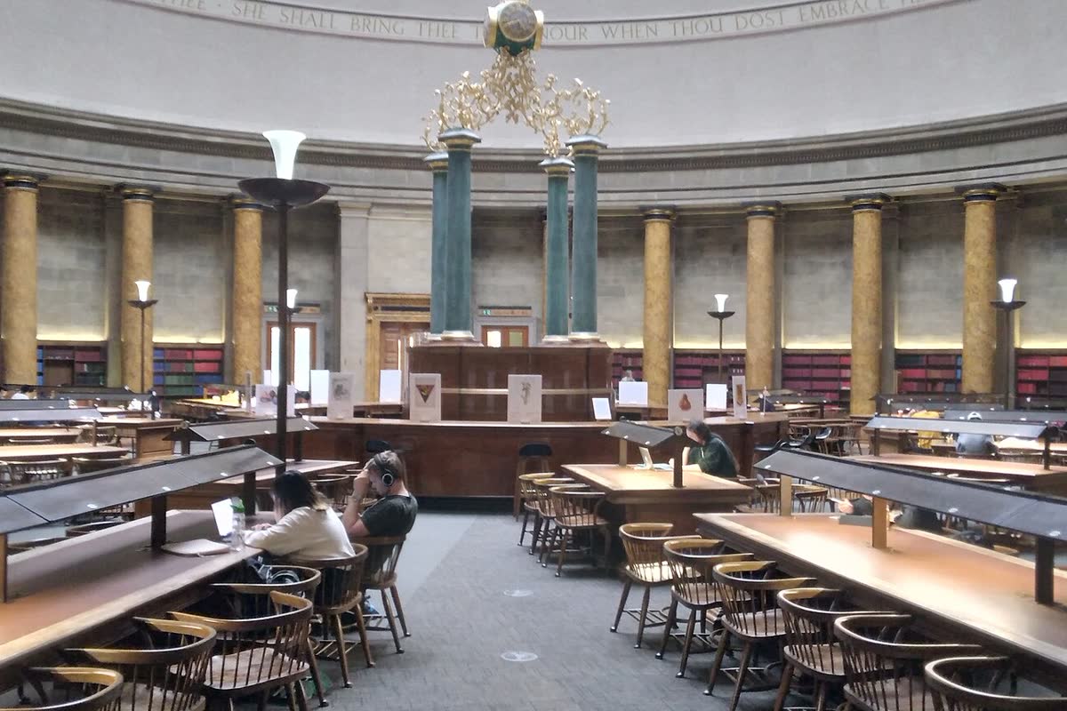 A public library reading room with people at long tables